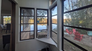 A room with a large window overlooking a lake, a 'WELCOME' sign, and a view of outdoor seating.