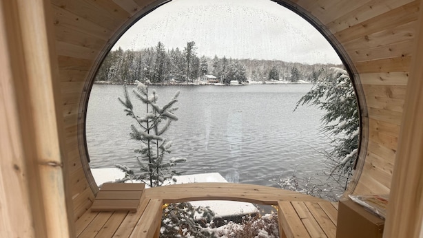 A circular wooden cabin with a view of a snow-covered lake and trees.