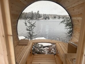 Una cabaña de madera circular con vistas a un lago nevado y árboles.