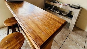 A compact kitchen with a wooden table, two stools, a microwave, a coffee maker, and a sink. - Ocean View (Monteverde)