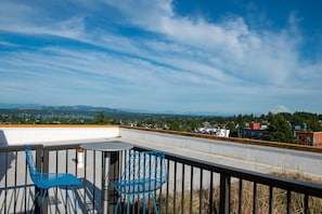 Eine Dachterrasse mit Tisch und Stühlen, die einen Blick auf die Stadt und einen Berg in der Ferne bietet.