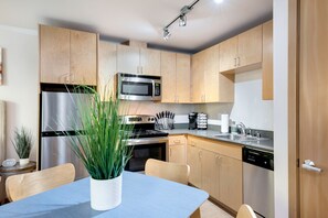 Eine moderne Küche mit Holzschränken, Edelstahlgeräten und einem Essbereich mit Tisch und Stühlen.