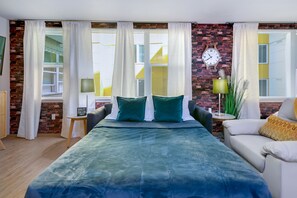 Ein Schlafzimmer mit einem großen Bett, einem Schlafsofa, einer Wanduhr und einer Ziegelwand.