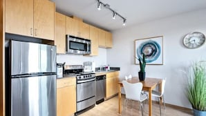 Una cocina moderna con electrodomésticos de acero inoxidable, armarios de madera y un comedor con mesa y sillas.