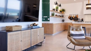 Ein modernes Wohnzimmer mit einem großen Fernseher, einer Holzkommode und einem bequemen Sessel.