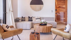 Ein modernes Wohnzimmer mit einer Eckcouch, zwei Ledersesseln, einem Couchtisch aus Holz und einer runden Wanddekoration.