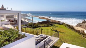Ein modernes Haus mit Pool, Terrasse und Meerblick.