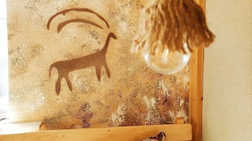 A rustic wooden bench with a patterned cushion and a wall with a goat silhouette.
