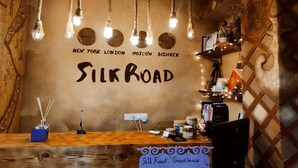 A cozy guesthouse interior with a wooden reception desk, a wall clock, and a sign indicating it's a guesthouse. - Silkroad Guest house (Bishkek)
