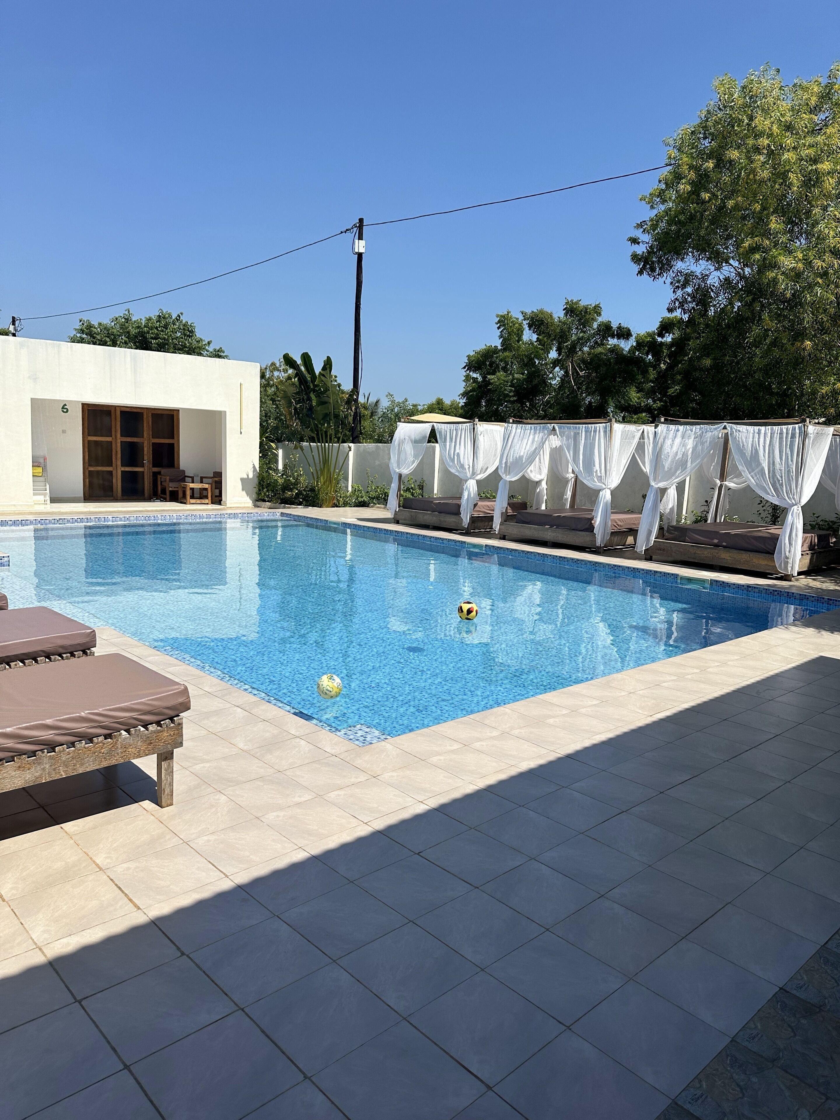 A swimming pool with lounge chairs and a covered seating area.