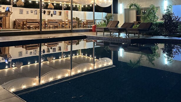 Ein Poolbereich mit Liegestühlen und einer überdachten Lounge mit Lichterketten.