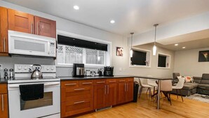 A modern kitchen with wooden cabinets, a white stove, and a dining area with a table and chairs.