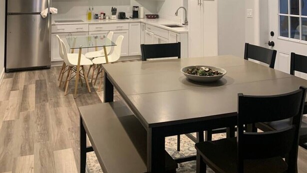 A modern kitchen with white cabinetry, a stainless steel refrigerator, and a dining area with a table and chairs. - Silver Spring Tranquil Bliss-2BR/1BA Nature/Access (Silver Spring)