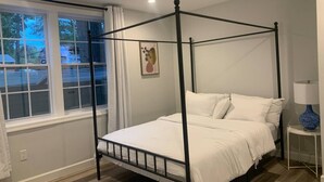 A four-poster bed in a bedroom with a window and a nightstand with a lamp. - Silver Spring Tranquil Bliss-2BR/1BA Nature/Access (Silver Spring)