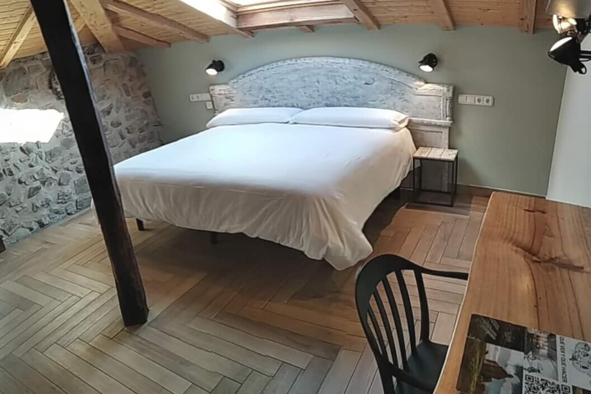 A bedroom with a bed, a wooden table, and a chair.