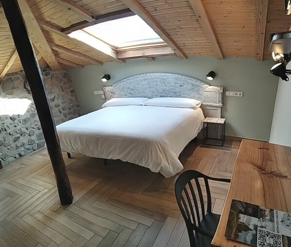 Un dormitorio con una cama, una mesa de madera y una silla.