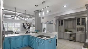A modern kitchen with blue cabinets, a large island, and pendant lighting. - LUXURY 6000 sqft Mansion Downtown Orlando 6BR/5BA SLEEPS 14  Arcade Rooftop Deck (Orlando)
