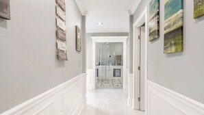 A hallway with a light-colored floor, white walls, and a door leading to a kitchen area. - LUXURY 6000 sqft Mansion Downtown Orlando 6BR/5BA SLEEPS 14  Arcade Rooftop Deck (Orlando)