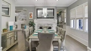 A dining room with a marble fireplace, a chandelier, and a long dining table with chairs. - LUXURY 6000 sqft Mansion Downtown Orlando 6BR/5BA SLEEPS 14  Arcade Rooftop Deck (Orlando)