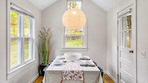 Un coin repas avec une table dressée pour quatre personnes, un grand saladier et un luminaire suspendu.