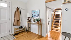 Une pièce dotée d’un plancher en bois, d’un porte-manteau, d’une console sur laquelle se trouve une lampe, d’un tableau encadré et d’un escalier avec des rampes en bois.