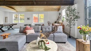 Un salon moderne avec un canapé gris, une table basse ronde et une poutre en bois au plafond.