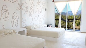 Un dormitorio con dos camas, un ventanal con vistas a palmeras y montañas, y una hamaca en el exterior.