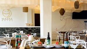 Un comedor con una mesa preparada para dos personas, mostrando diversos platos, bebidas y aderezos.