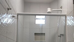 A small, enclosed shower stall with a toilet and a window. - Casa Inteligente (Japaratinga)