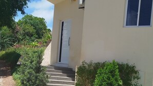 A building with a paved entrance and a door leading to the interior. - Casa Inteligente (Japaratinga)