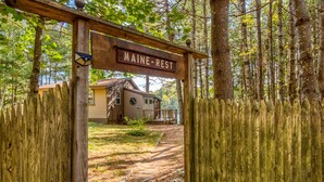 A wooden archway with a sign reading "MAINE-REST" leading to a house with a porch. - Lakefront Cottage with Private Dock  and Kayaks. Dog-Friendly (Newfield)