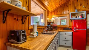 A wooden-paneled kitchen with a red refrigerator, a toaster, and shelves with containers. - Lakefront Cottage with Private Dock  and Kayaks. Dog-Friendly (Newfield)