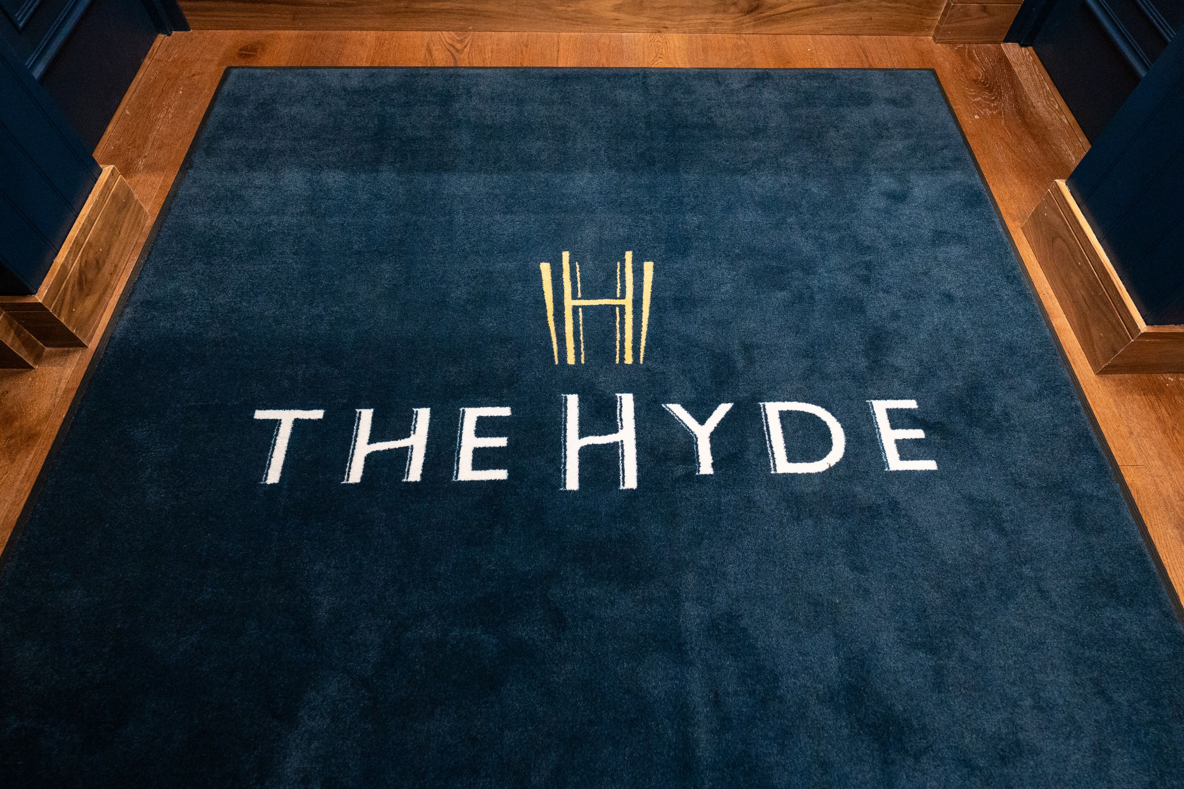 A dark blue carpet with "THE HYDE" and a stylized 'H' logo.