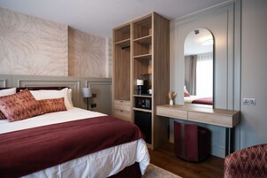 Un dormitorio con cama, armario, escritorio y espejo.