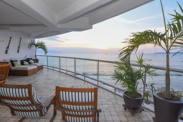 A balcony with wicker furniture, potted plants, and a view of the sea. - Beachfront Condo in Nuevo Vallarta (Nuevo Vallarta)