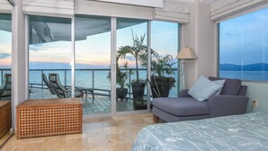Un balcon avec vue sur la mer, un canapé, un lit et une table.