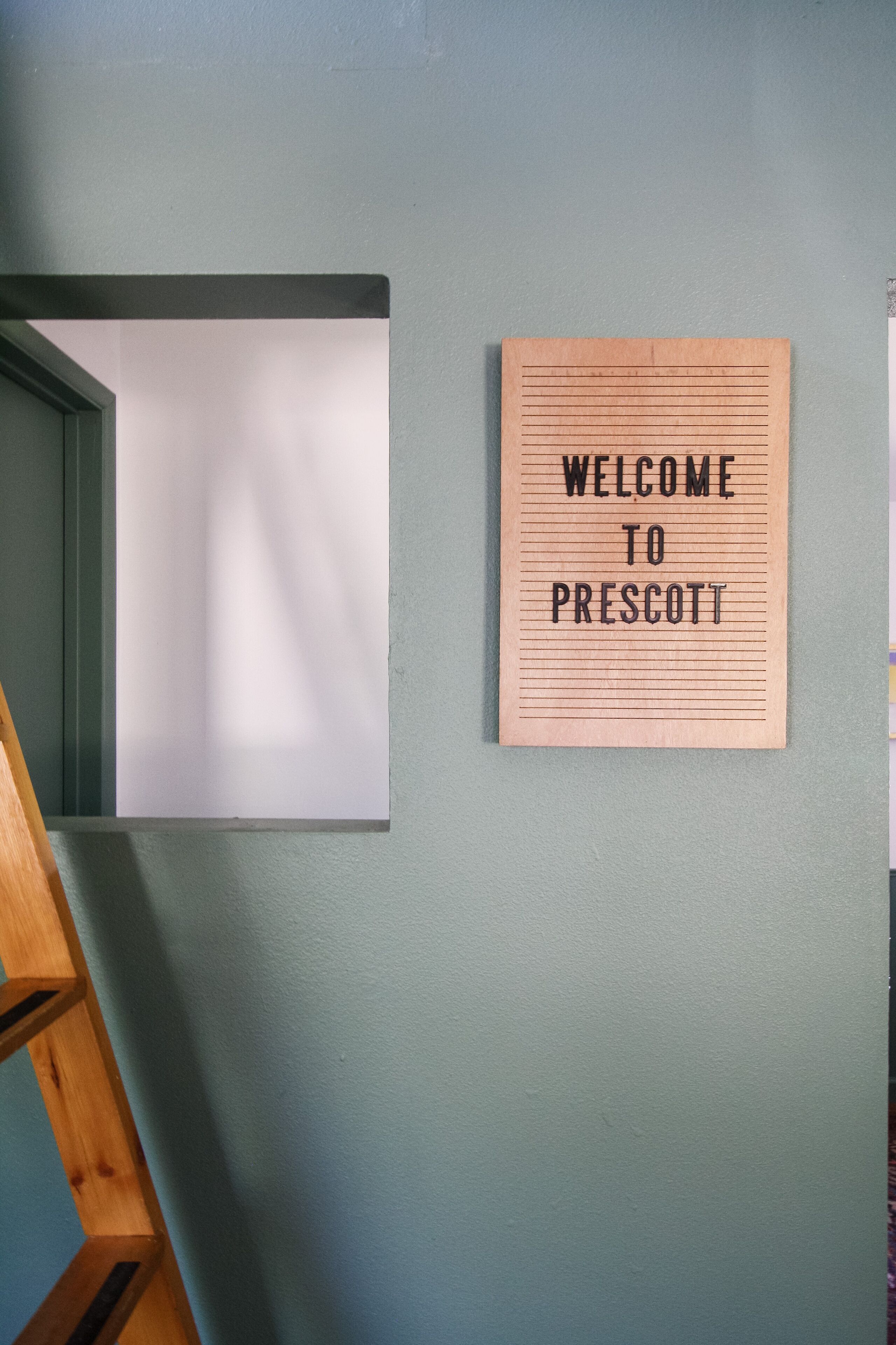 A welcome sign on a wall with a wooden frame and horizontal lines.