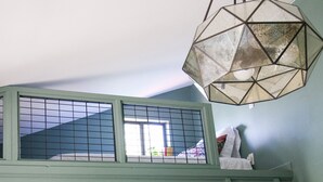 A room with a window, a geometric hanging light fixture, and a ladder against the wall. - Perfectly located with 2 bike cruisers available to help you explore the town! (Prescott)