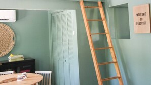 A room with a wooden ladder, a round table with chairs, a hanging light fixture, and a welcome sign on the wall. - Perfectly located with 2 bike cruisers available to help you explore the town! (Prescott)