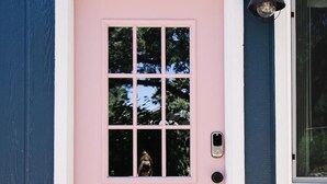 A pink door with a window, a doormat with "HEY Y'ALL" text, and a wall-mounted light fixture. - Perfectly located with 2 bike cruisers available to help you explore the town! (Prescott)
