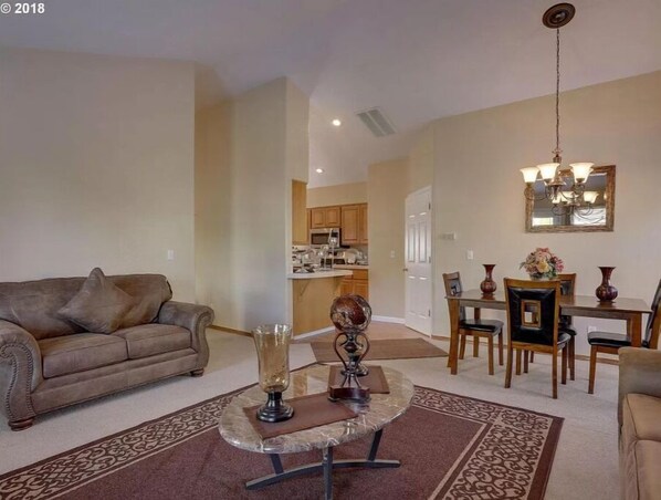 A living room with a sofa, a coffee table, and a dining area with chairs and a table.