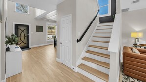 A modern interior with a staircase, a door, a plant, and a sofa. - The Haven - King Beds - Games - Office - BBQ - Yard (Forney)