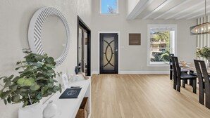 A modern interior with a dining area, a large mirror, and a potted plant. - The Haven - King Beds - Games - Office - BBQ - Yard (Forney)