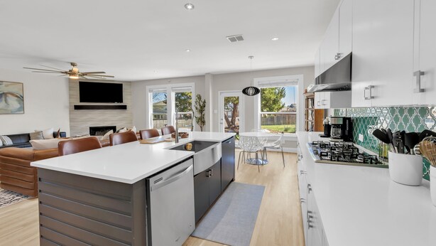 A modern kitchen with a central island, white cabinetry, and a dining area with a table and chairs. - The Haven - King Beds - Games - Office - BBQ - Yard (Forney)