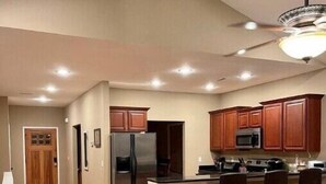 Una cocina moderna con armarios de madera, un refrigerador de acero inoxidable y una isla central con taburetes de bar.