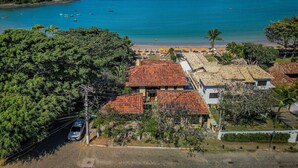 Una propiedad costera con vista a la playa, patio cercado y edificio con techo de tejas rojas.