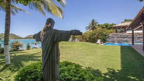 Una estatua en un jardín cuidado con una piscina y un muro de piedra.