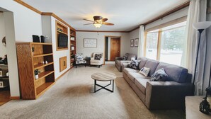 Ein Wohnzimmer mit einer Holzregal, einem Sofa, einem Couchtisch und einem Deckenventilator.