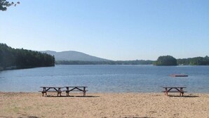Vista con lago, mesas de picnic y un bote en el agua.
