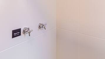 A shower with multiple faucets and a rain showerhead.
